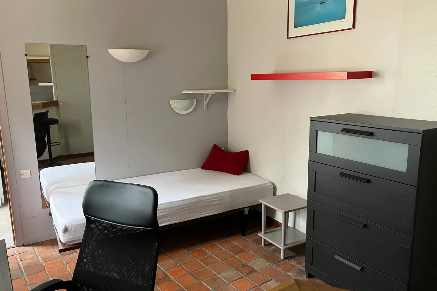 Coin nuit du studio avec lit, commode et miroir