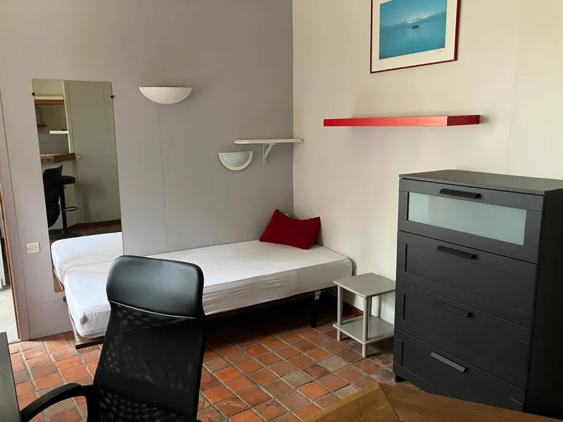 Coin nuit du studio avec lit, commode et miroir